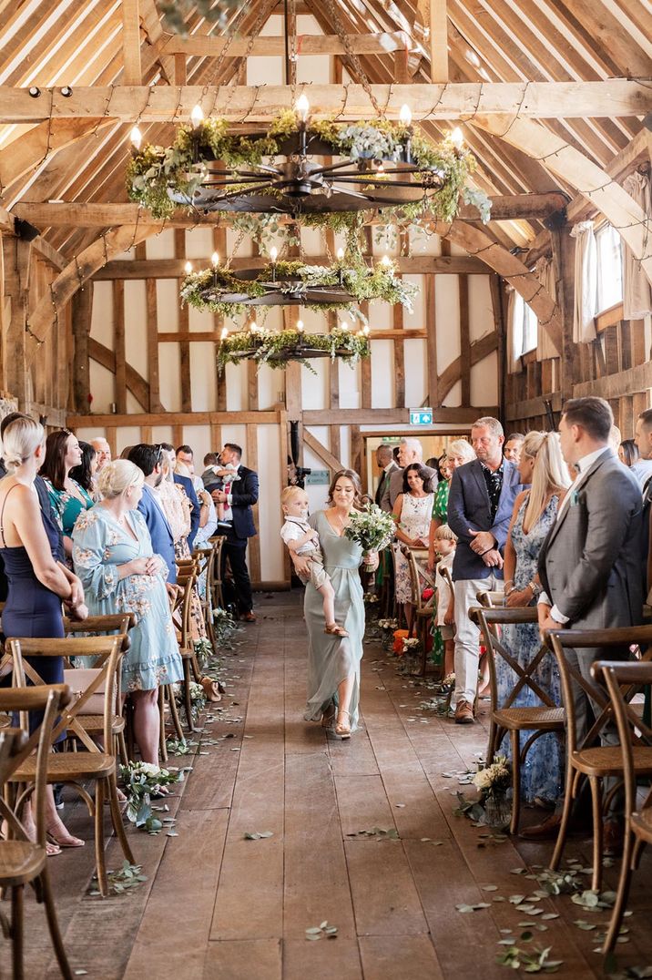 Gate Street rustic barn wedding venue with a bridesmaid walking down the aisle in a green dress 