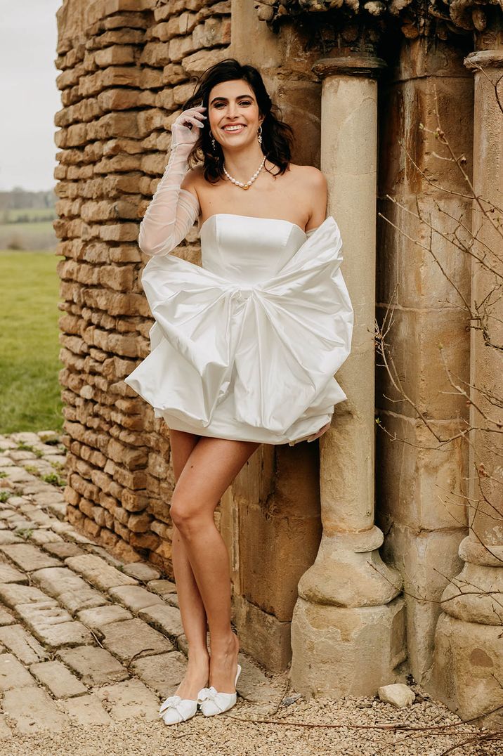 Bride wearing strapless short wedding dress with statement bow detail 