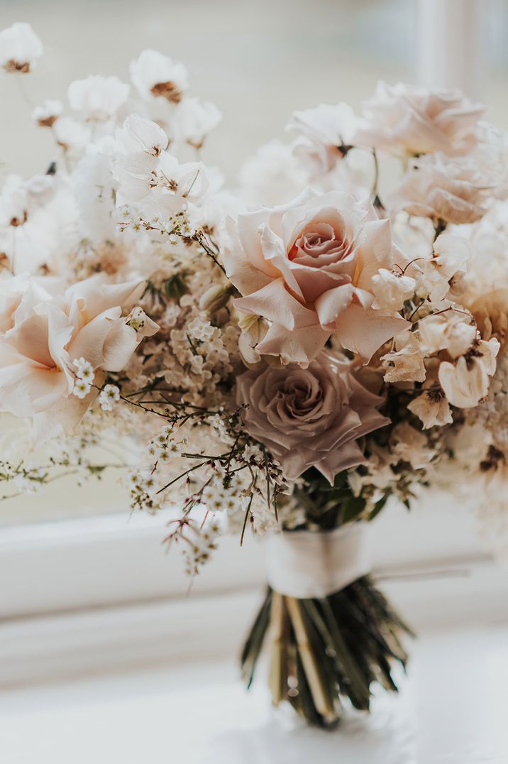 Light pink roses and white wax flower make up bridal bouquet 