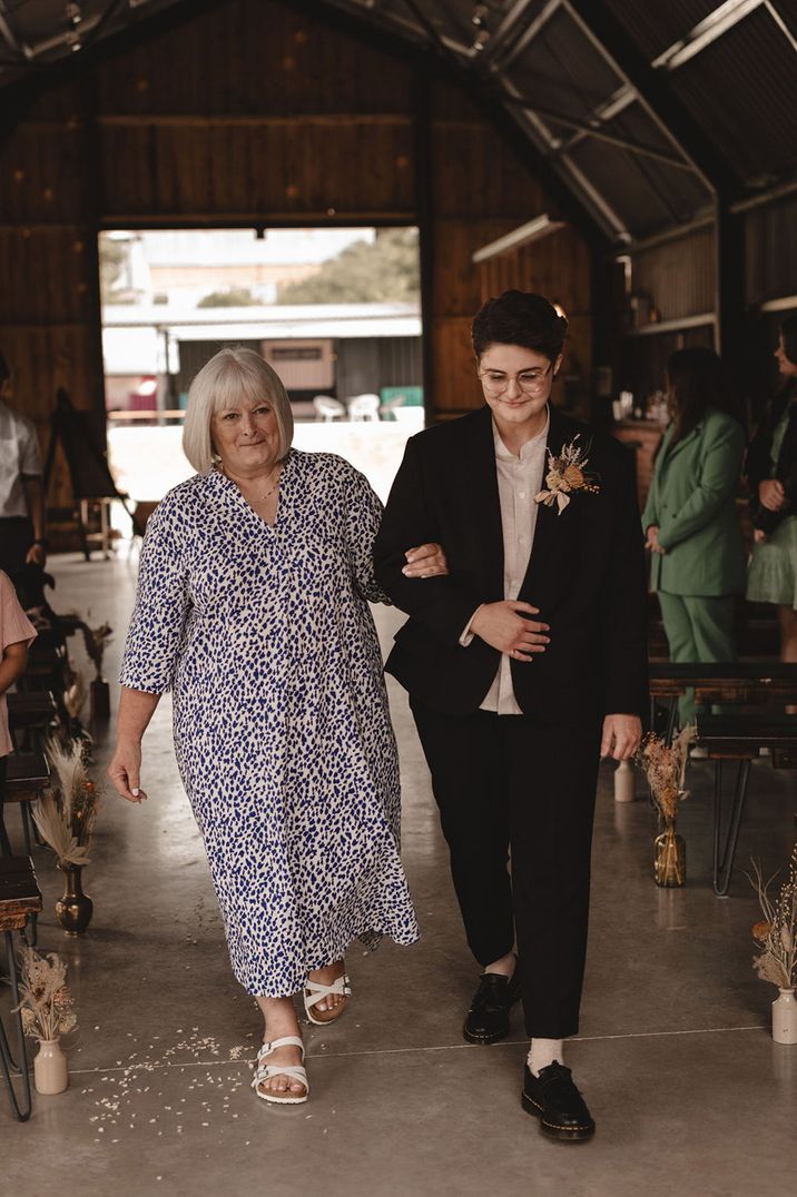 Mother of the bride walks the bride down the aisle at industrial wedding venue 