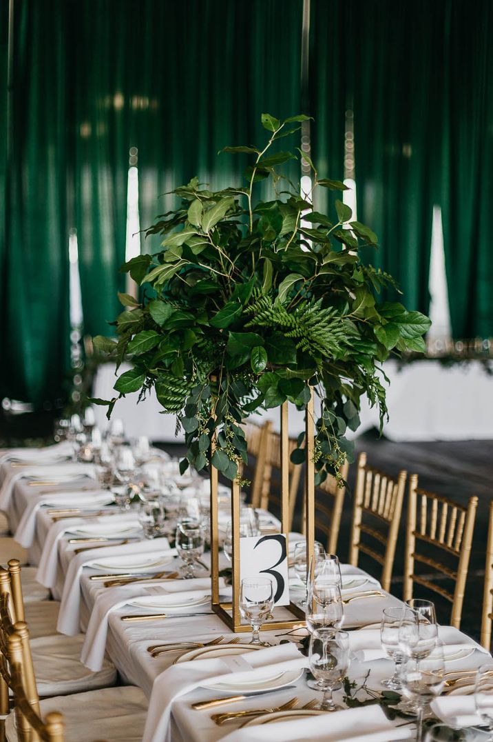 Dark green and gold wedding table spread with foliage