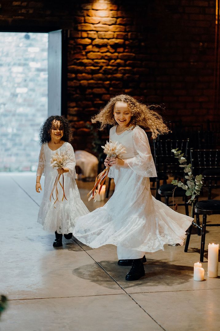 Two young bridesmaids wearing white bridesmaid dresses, twirling and dancing