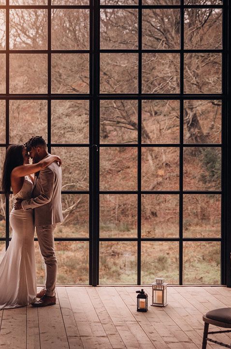 Bride in halter neck wedding dress and white Dr Martens with groom in grey three piece suit at Hidden River Cabins