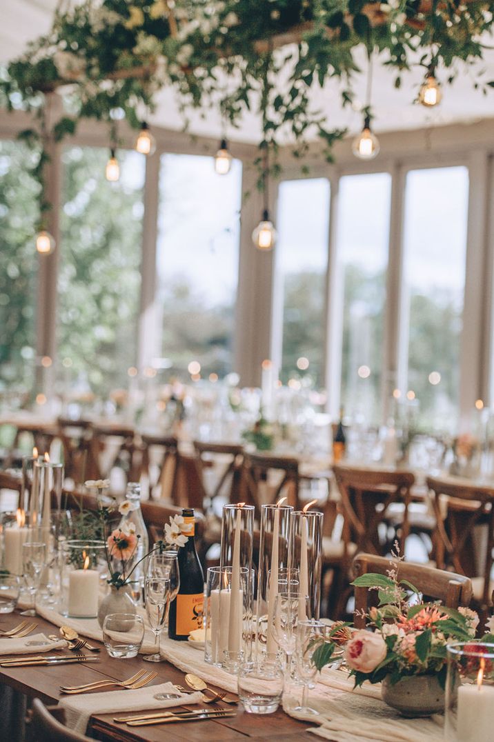 Simple and rustic wedding tablescape with white drapery and gold cutlery with neutral flowers 