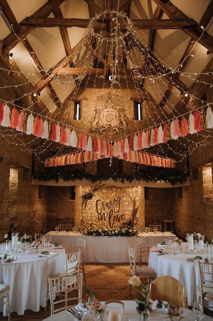 The Great The Barn wedding dress with tassel bunting, fairy lights and Crazy In Love top table backdrop sign 