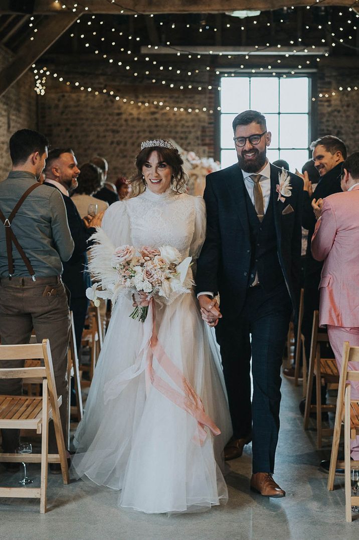 Couple walk down the aisle after hand fasting LGBTQI+ wedding ceremony 