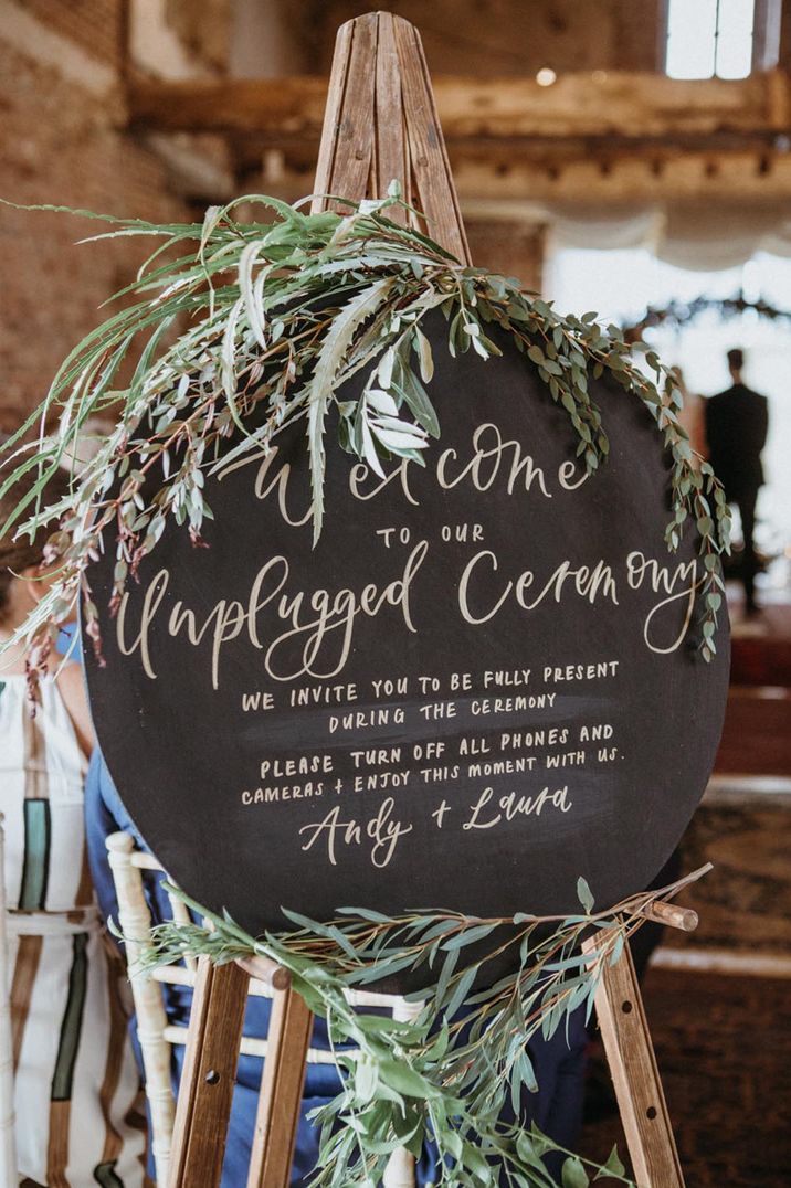 Black rounded unplugged wedding ceremony with green foliage 