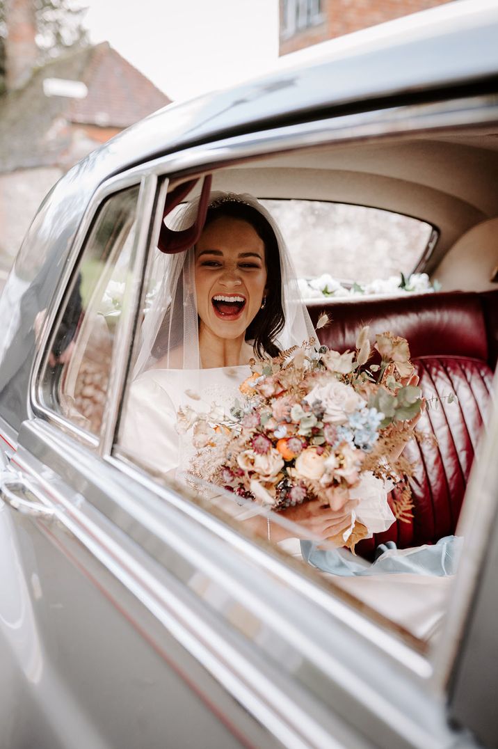 Bride sits in the wedding car excited for her wedding day