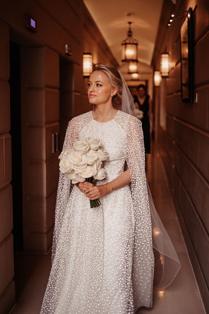 Bride wears pearl embellished wedding dress and cape 