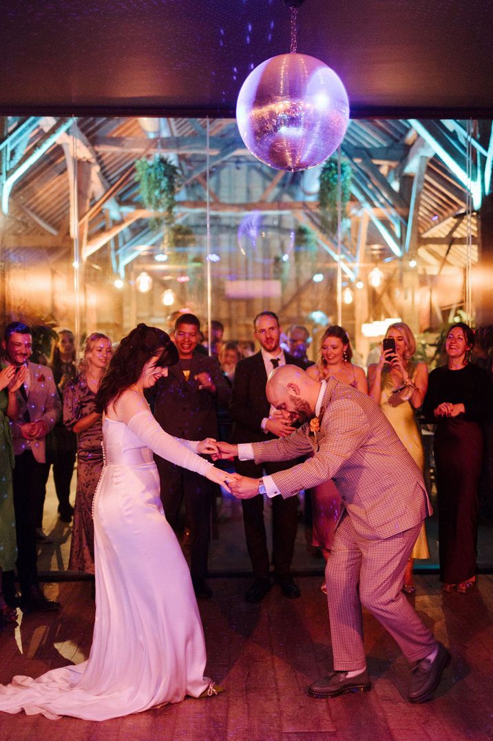 The bride and groom perform their first dance together under a disco ball 