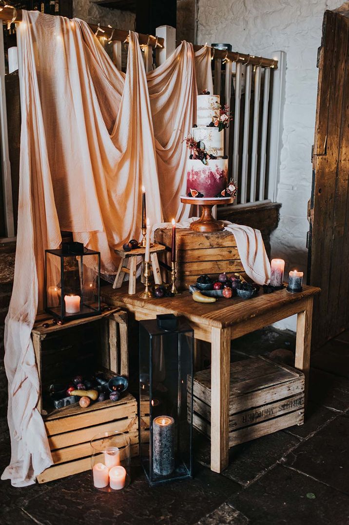 Three tiered purple ombre wedding cake with autumnal candles and drapery