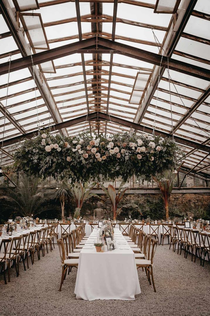 Glass house wedding venues - suspended rose and foliage wedding decor and white neutral wedding tablescapes 