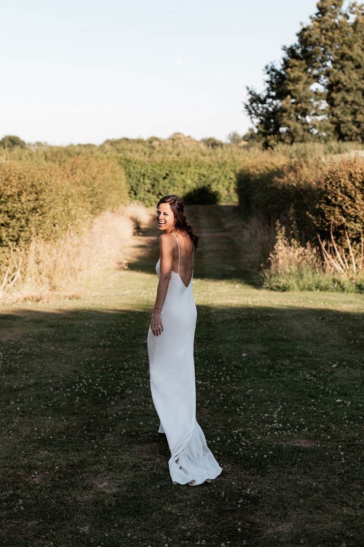 Martial arts bride, Chloe Bruce, wearing an open back satin slip wedding dress for barn wedding 