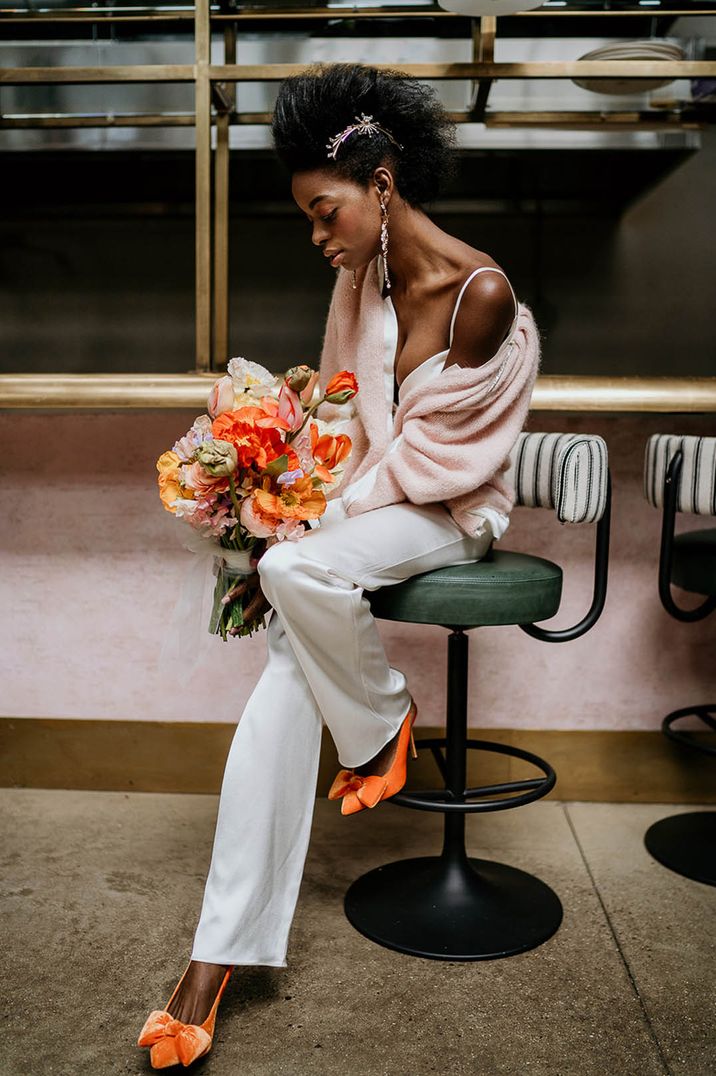 Bride wearing trousers outfit with orange slingback heels and orange bouquet 