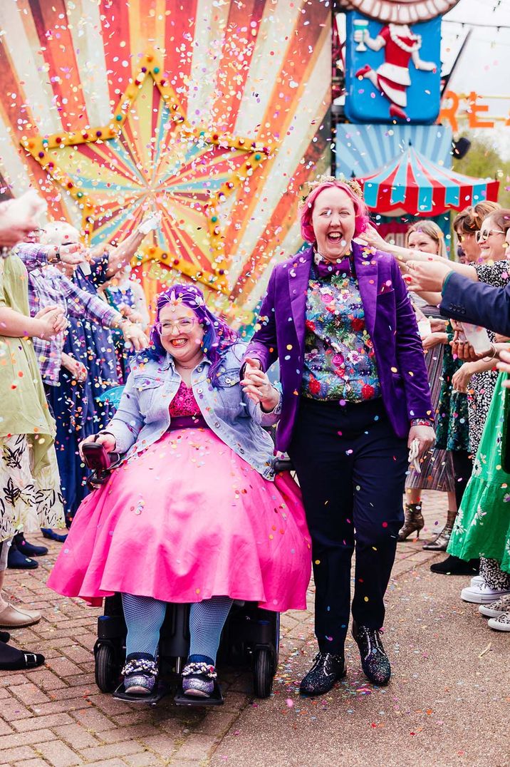 Two brides at colourful pink and purple theme wedding decor at a theme park 