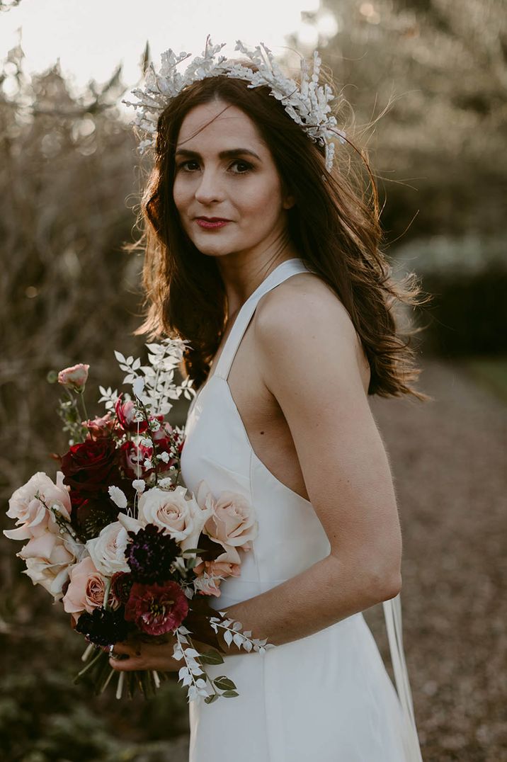 Bride carrying pink and red rose wedding bouquet in white wedding dress with flower crown accessory 