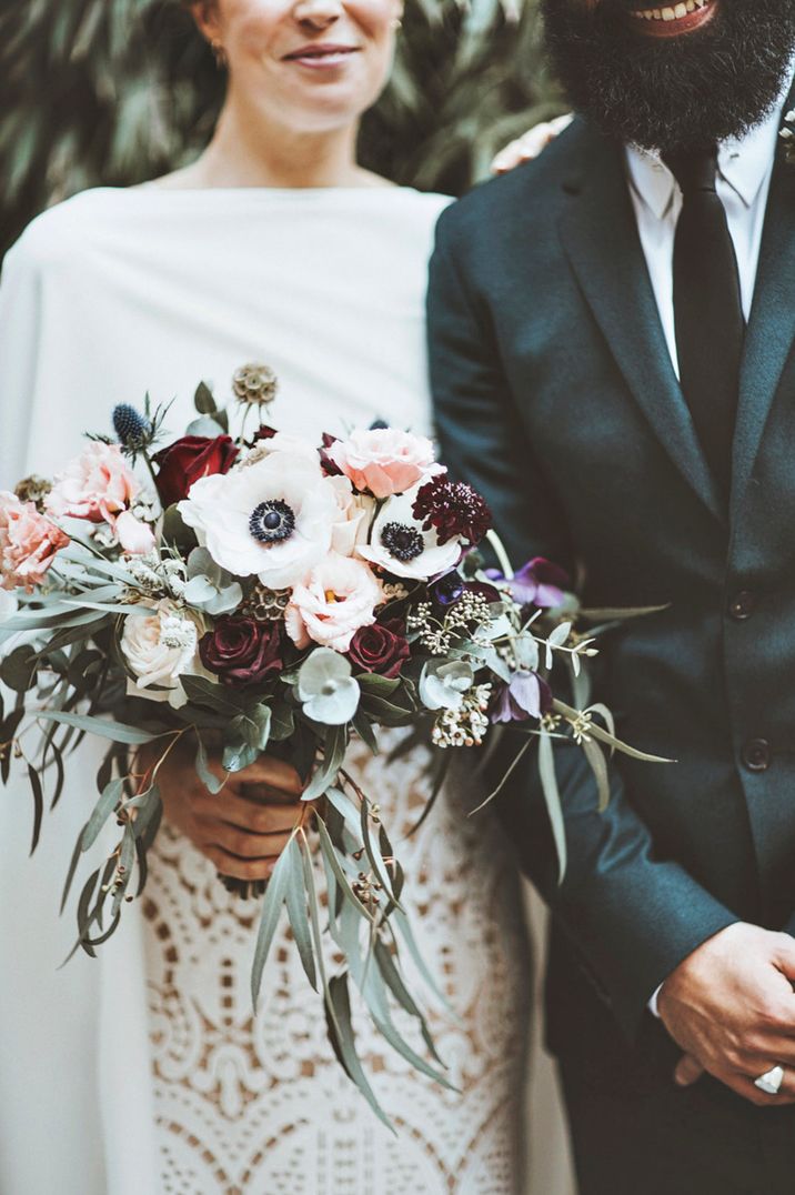 Bride holding red and white winter wedding bouquet with anemones and roses 