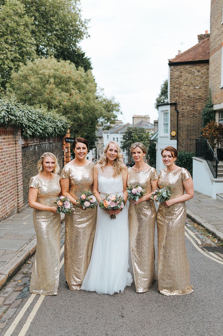 Bridesmaids wearing gold sparkly sequin dresses standing with bride wearing a white wedding dress