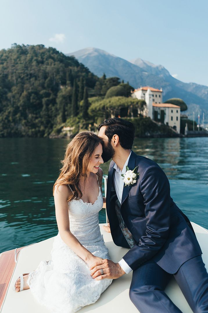 Bride in strappy lace wedding dress and groom in dark blue suit on a boat on Lake Como