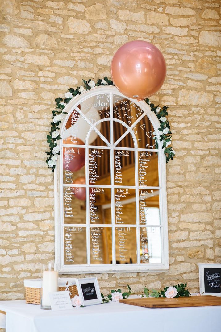 Window arch mirror with white flowers and a balloon seating chart 