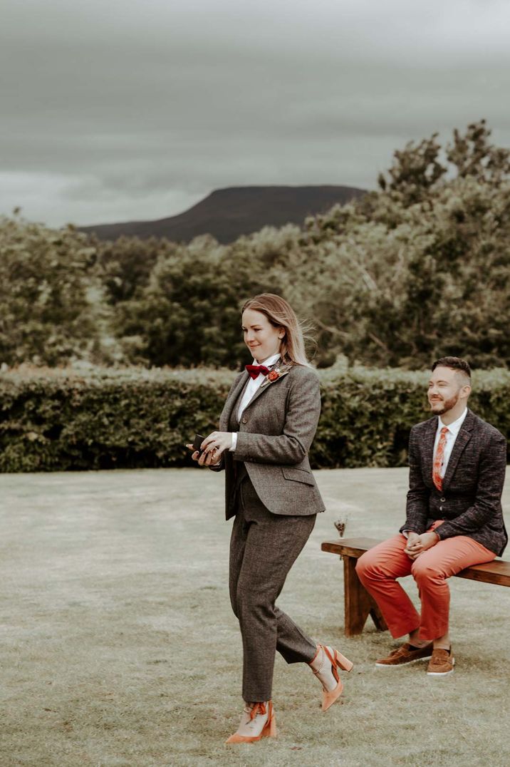 Groomswoman wearing tweed suit, white shirt, red tie and velvet orange heels at Eden Barn socially distanced wedding