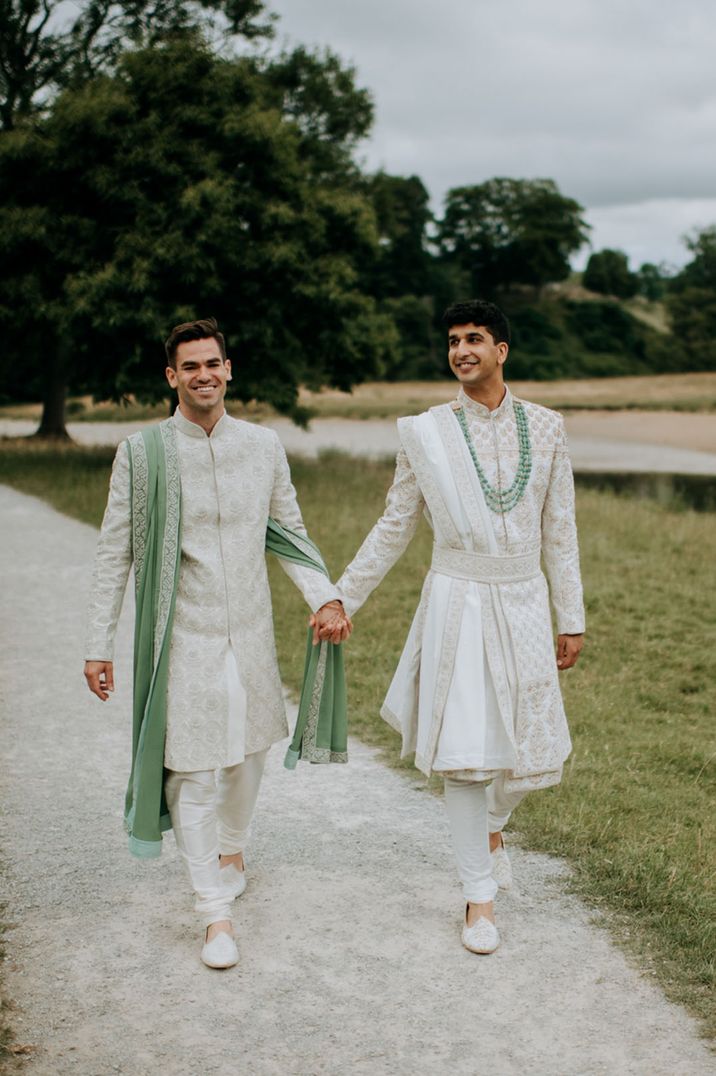 Two grooms walking holding hands for their wedding under 40k at Tithe Barn