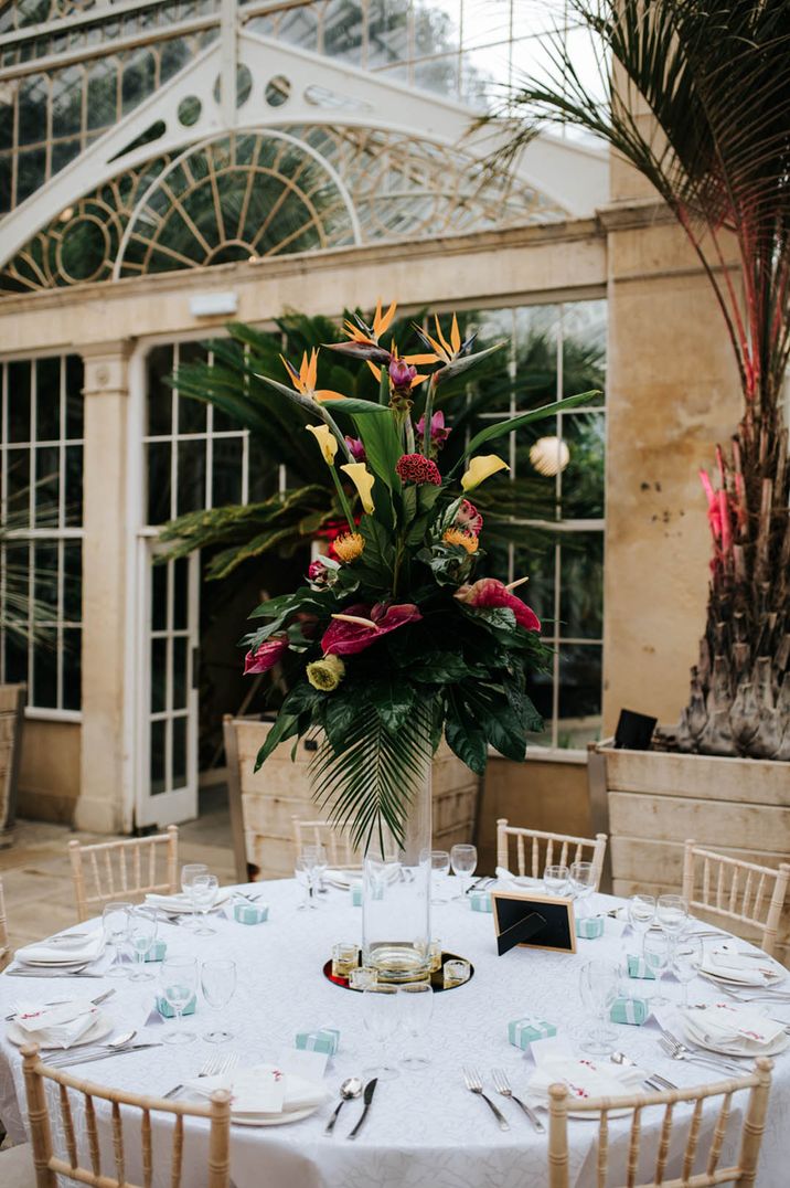 Syon Park wedding venue with tropical wedding flower centrepiece on tall hurricane vase 