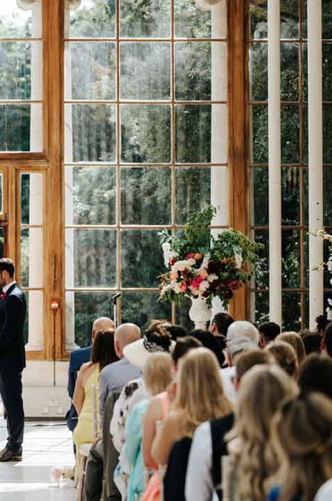 Groom in dark suit and bride in long sleeve lace wedding dress at the alter of Kew Gardens London wedding venue 