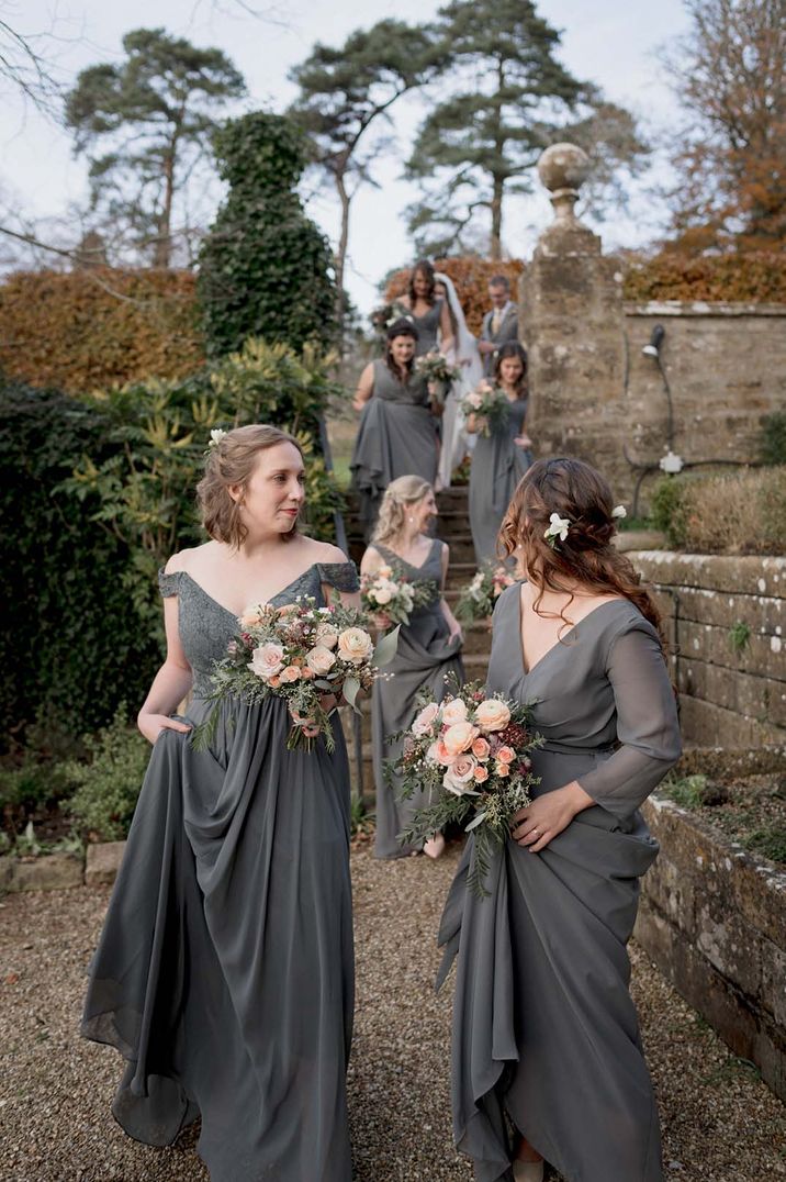 Brides descending the stairs wearing mismatched dark grey bridesmaid dresses 