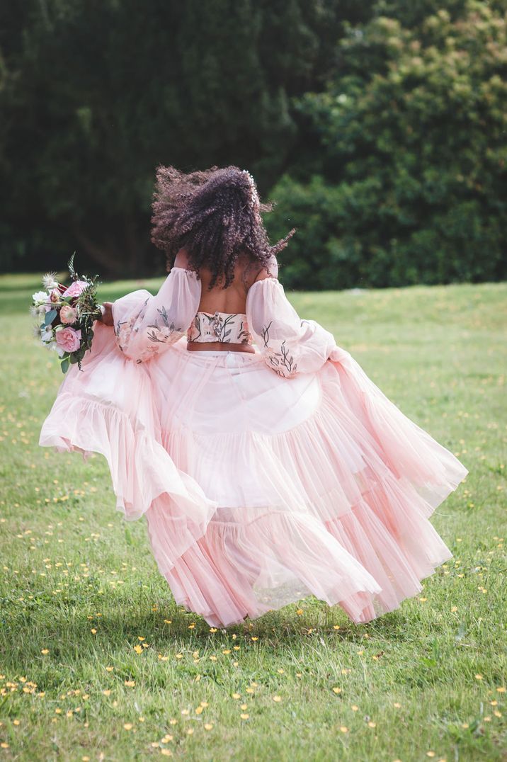 Black bride with afro hair in a coloured wedding dress with embroidered design and removable sleeves