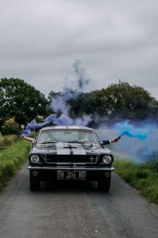 Fun couples wedding portrait in a Mustang car with smoke grenades 