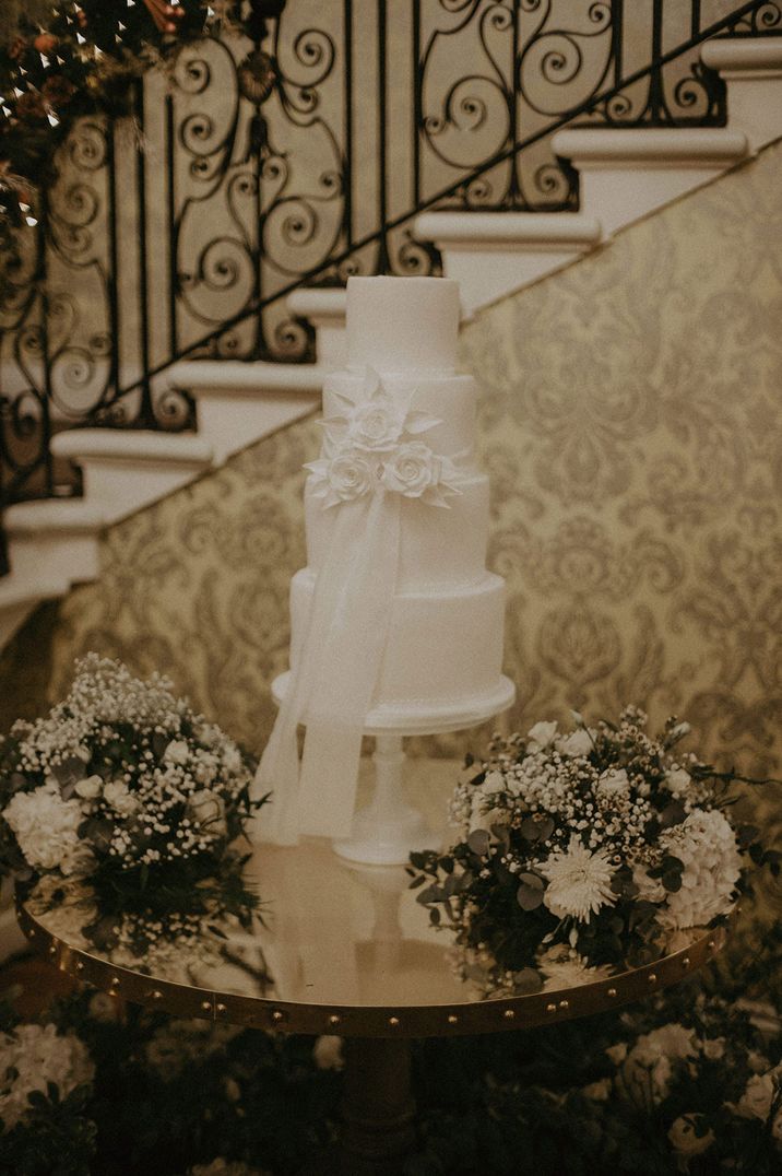 Three tier white cake with flower details at traditional wedding