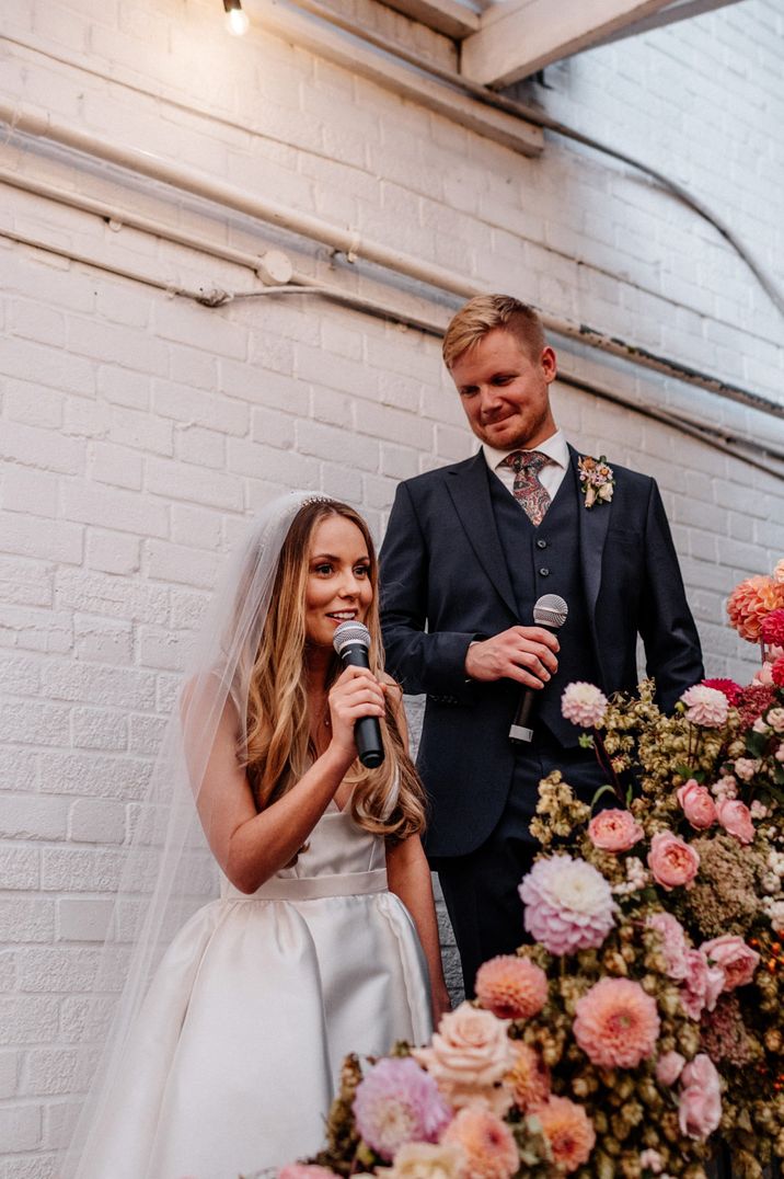 Bride in long sleeveless wedding dress and groom giving speeches 