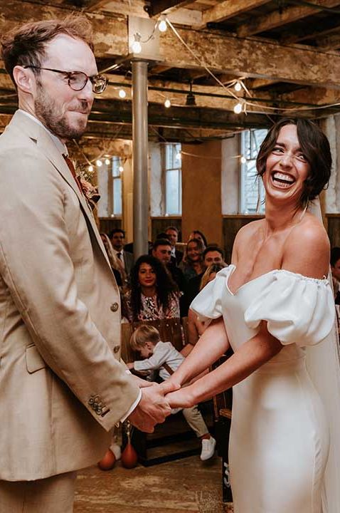 Civil wedding ceremony in an industrial wedding venue with bride in an off the shoulder wedding dress