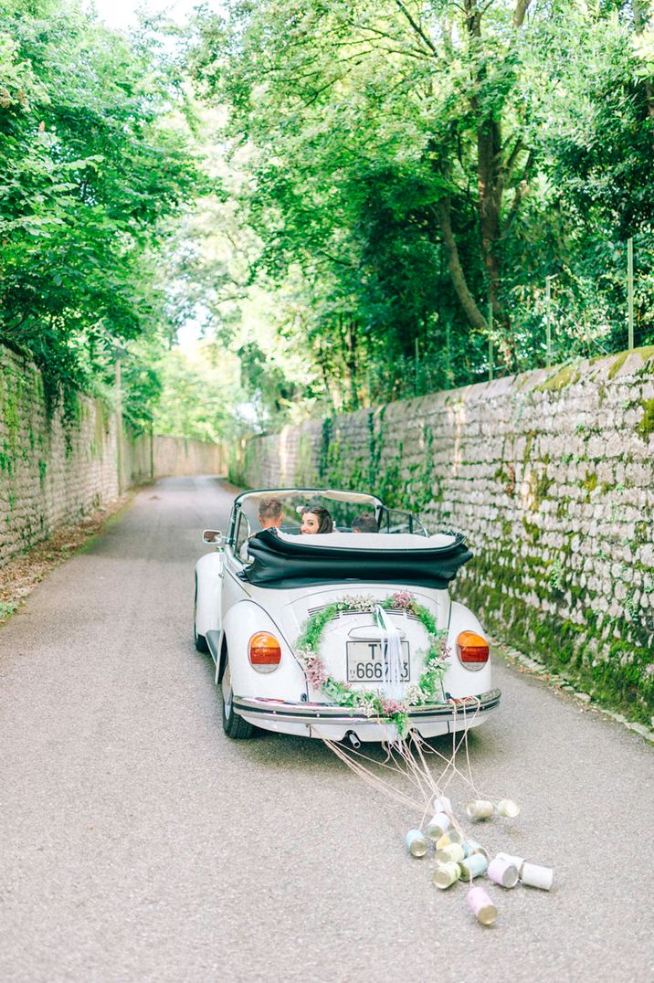 White convertible wedding car with floral heart wreath and tin cans decorations