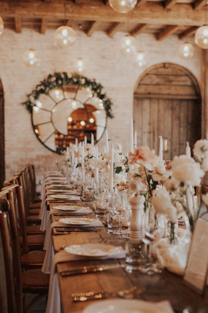 Neutral toned wedding tablescape with white roses and long candle centrepieces 