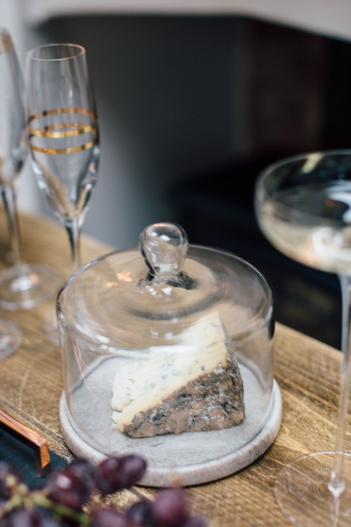 Glass cheese dome on marble slate stand with block of cheese inside at Christmas soiree 