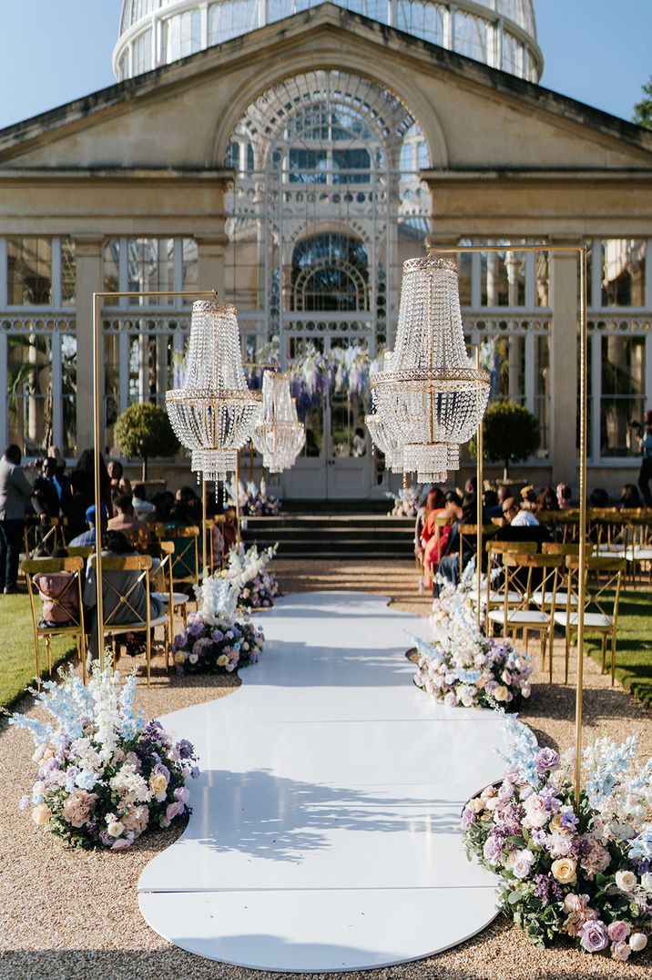 Pastel blue, purple and white wedding flower aisle decorations with chandeliers for outdoor ceremony 