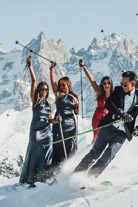 Unique ski wedding in the alps with the groom skiing past the bridesmaids in satin dresses 