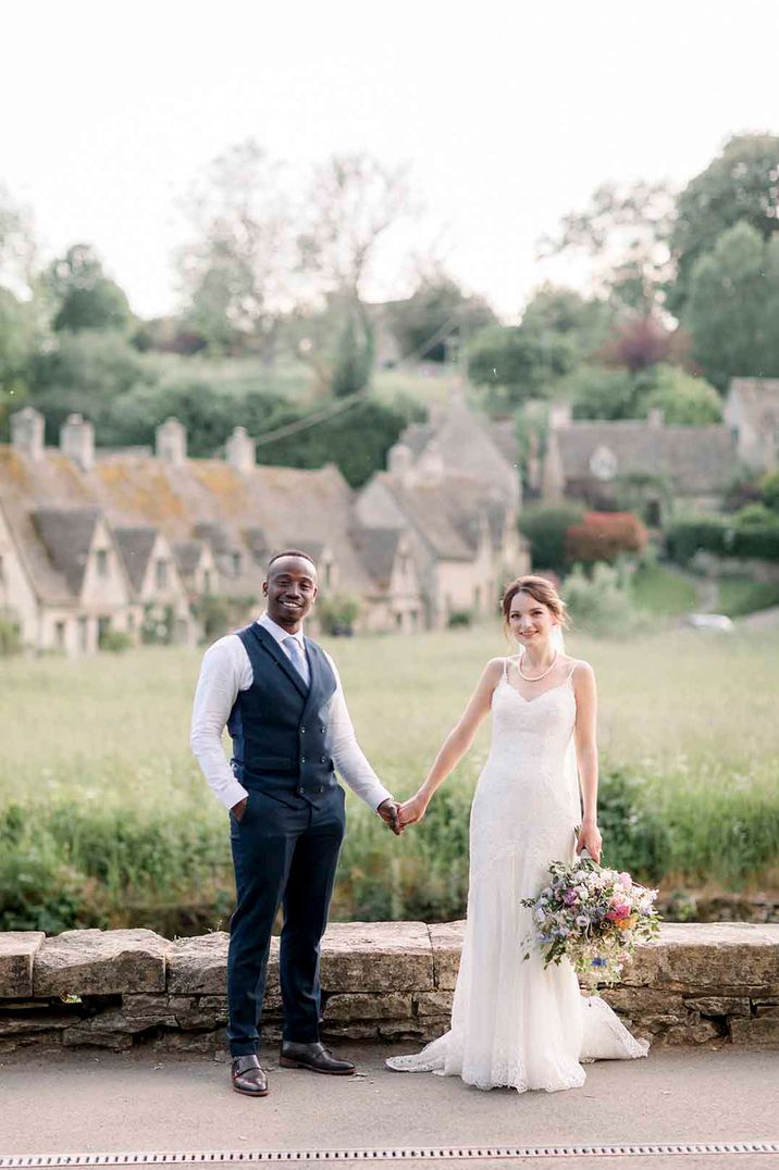 Couple walk through the Cotswolds at their traditional wedding