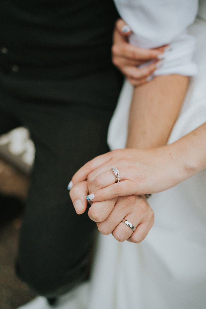 Bride and groom holding hands bearing their new wedding rings