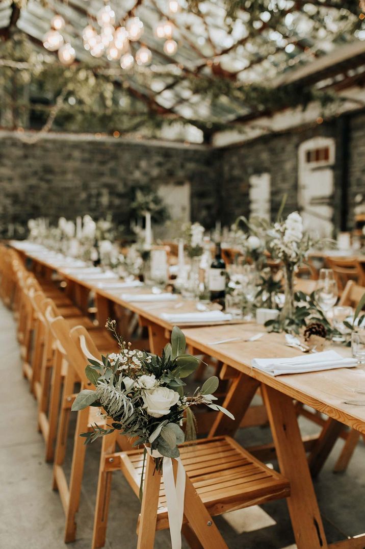 Earthy, rustic themed wedding tablescape with lots of foliage decorations and fairy lights