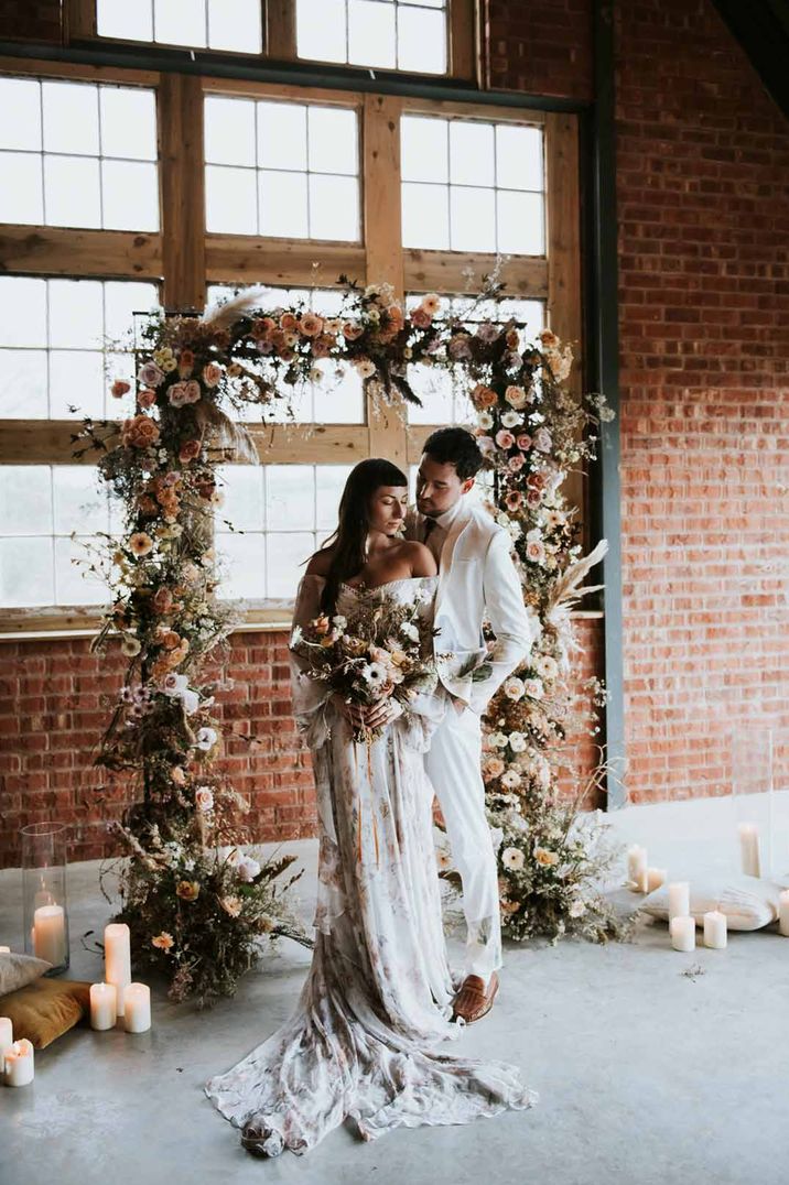 Bride and groom standing at the alter of The Giraffe Shed wedding venue with square dried flower floral arch and pillar candles