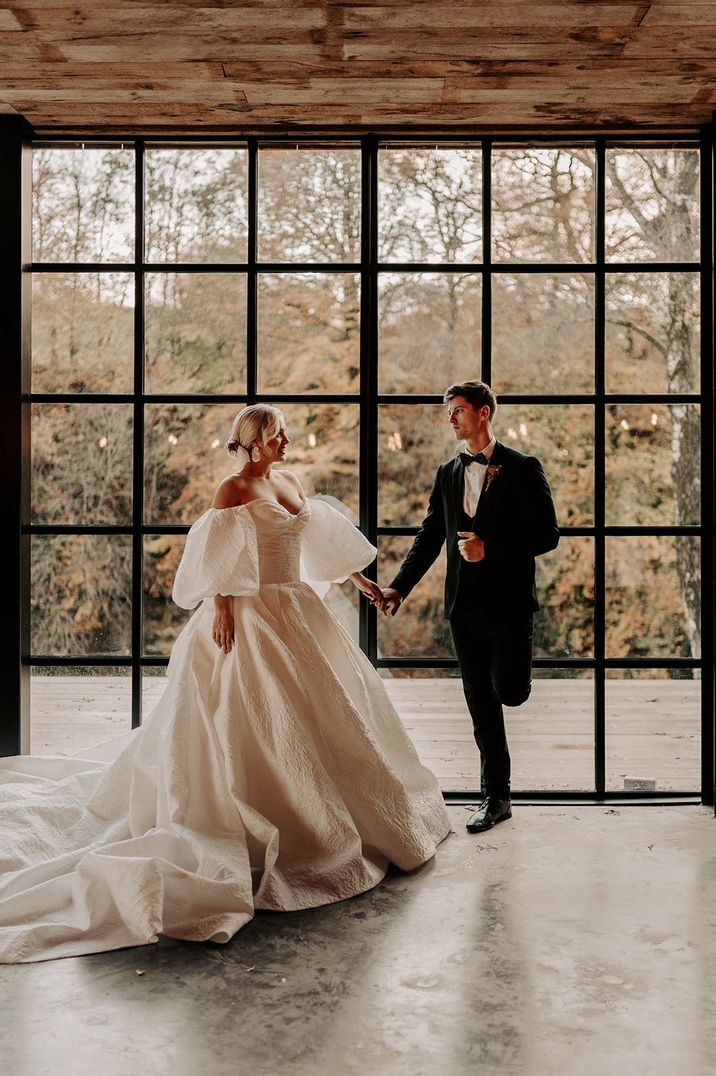 Bride in statement pufff sleeve wedding dress dancing at Hidden River Cabins in the Lake District 