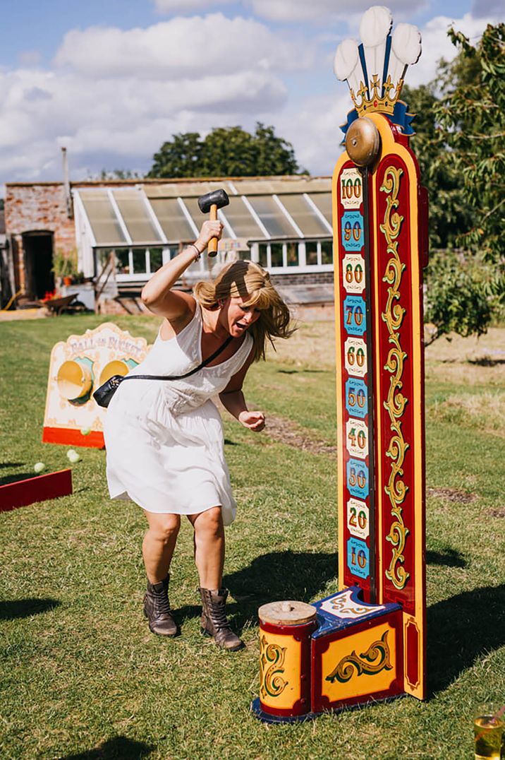 Wedding guest playing high striker hammer game at carnival theme celebrations 