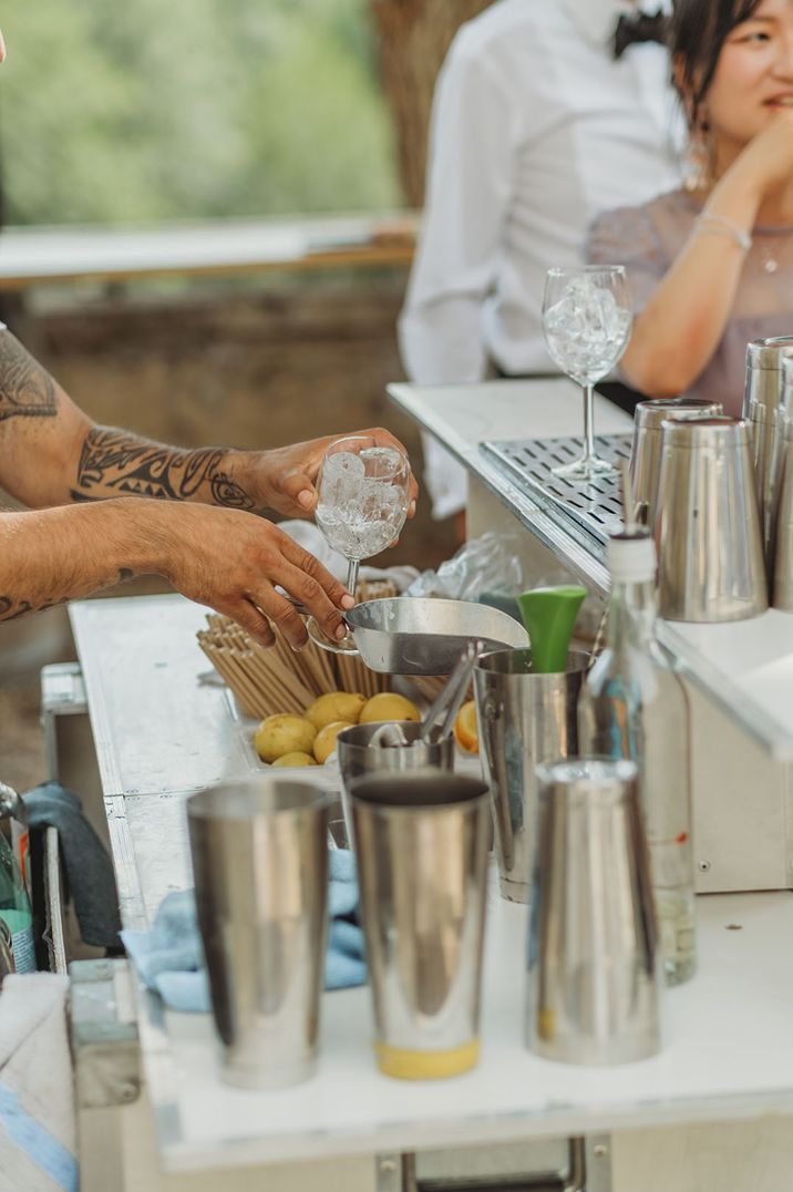 Mixologist makes wedding cocktails at outdoor cocktail cart bar 