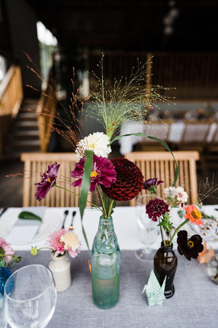 Bottles filled with flower stems for rustic wedding reception at Stone Barn 