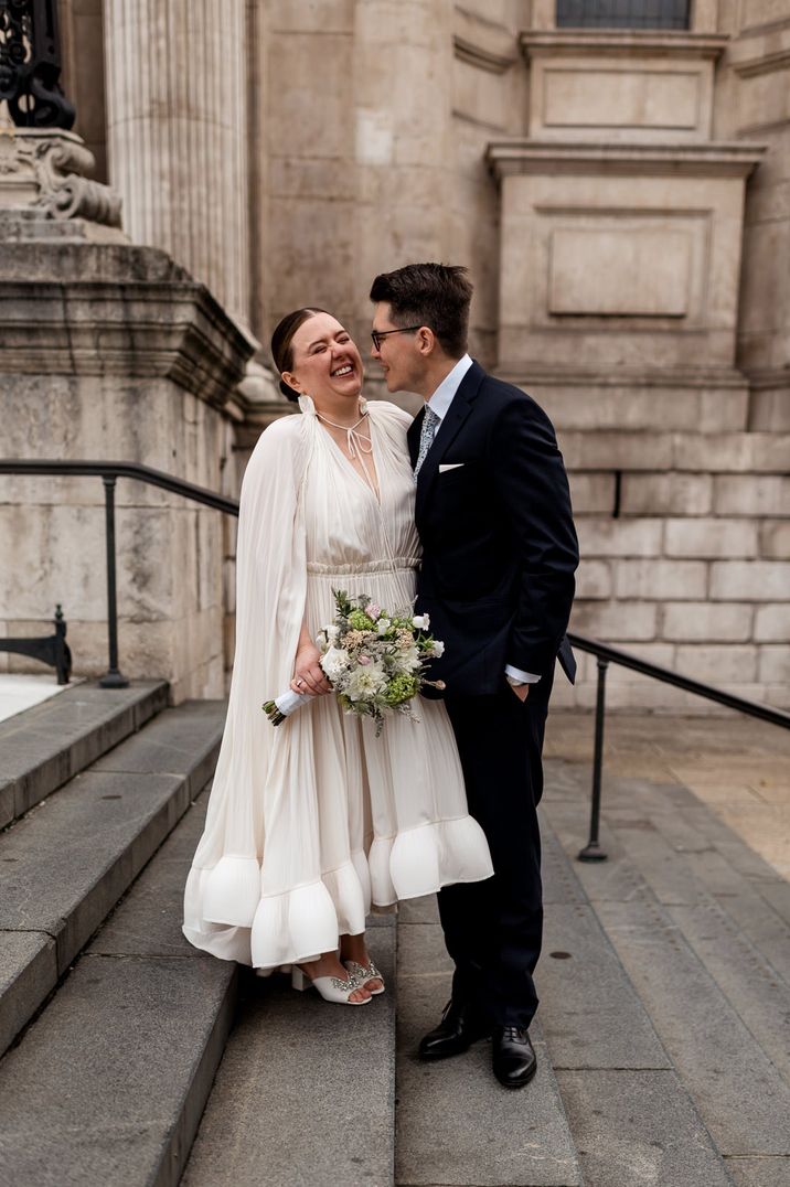 Bride laughing in a Lanvin wedding dress and groom in a blue suit and patterned tie 