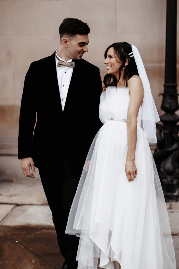 Pregnant bride poses with groom for their couple portraits 