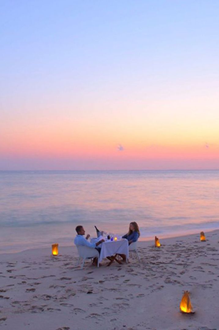 Dreamy sunset beach landscape as two newlyweds sit not he beach together on their honeymoon 